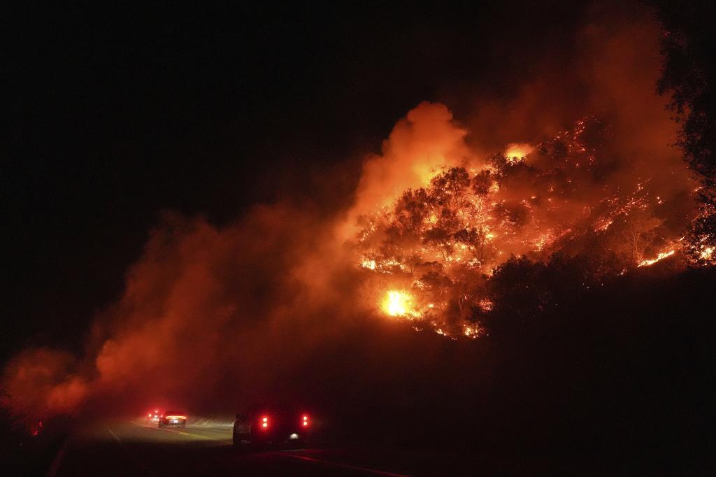 Vehicles pass through smoke from the Lilac Fire in Bonsall