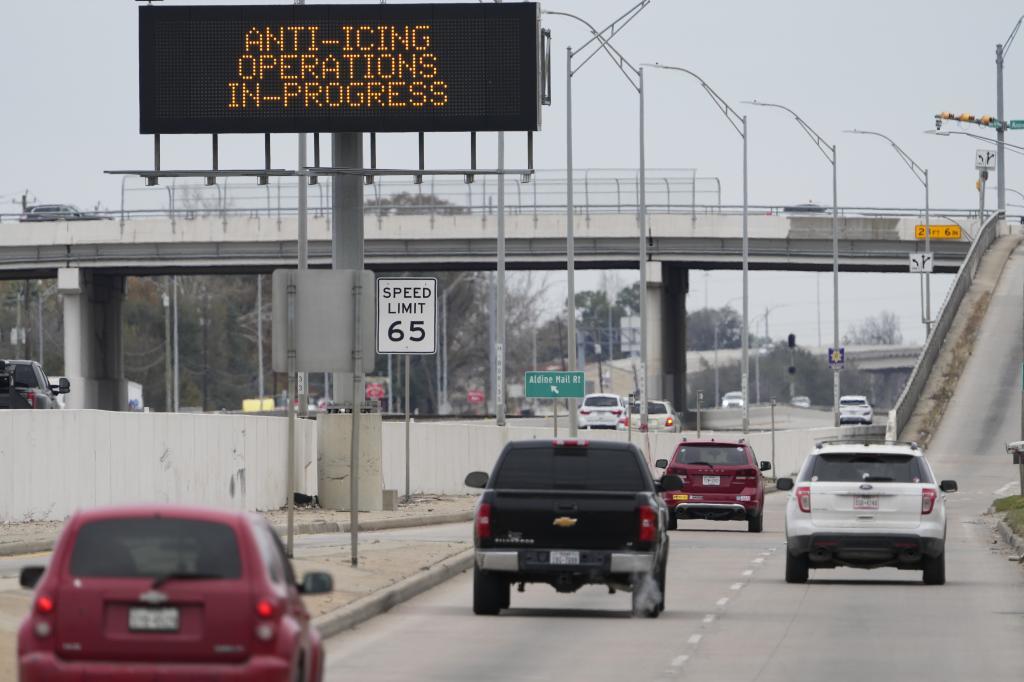 Vehicles pass a sign displaying Winter storm related operations Monday