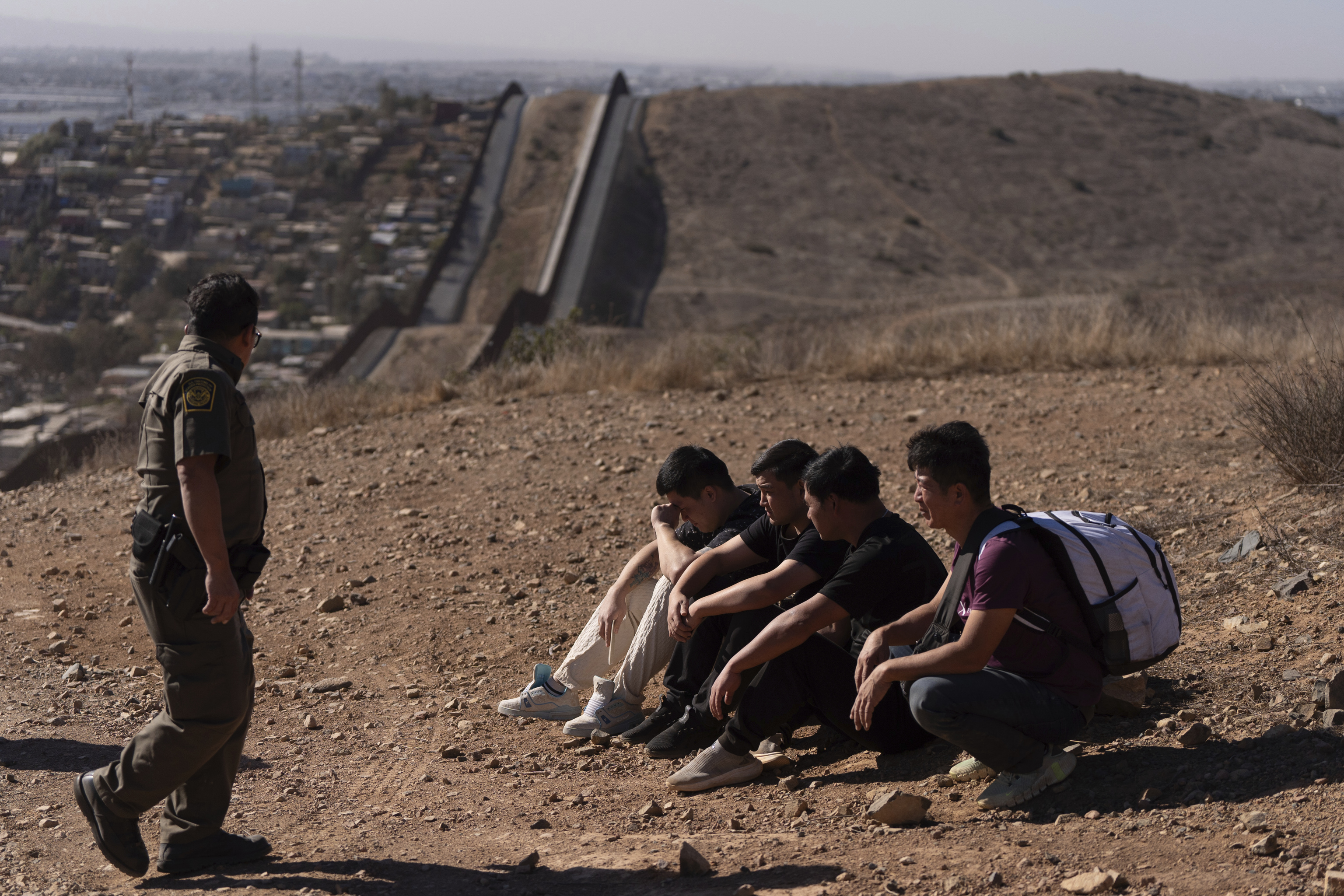 Border Patrol Agent walks past four men detained after crossing the border illegally.