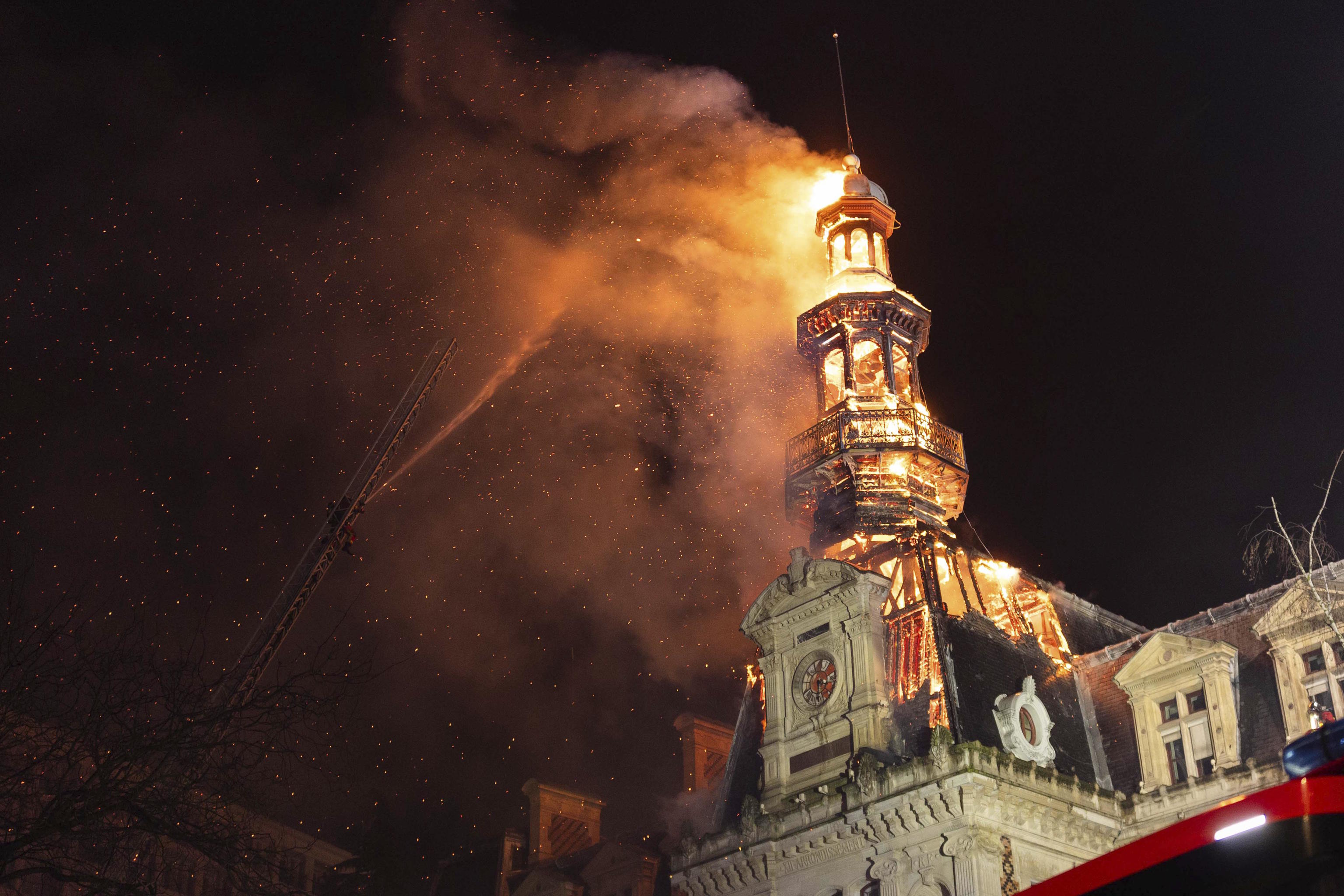 The roof and the spire of the Paris 12th district town hall burning.