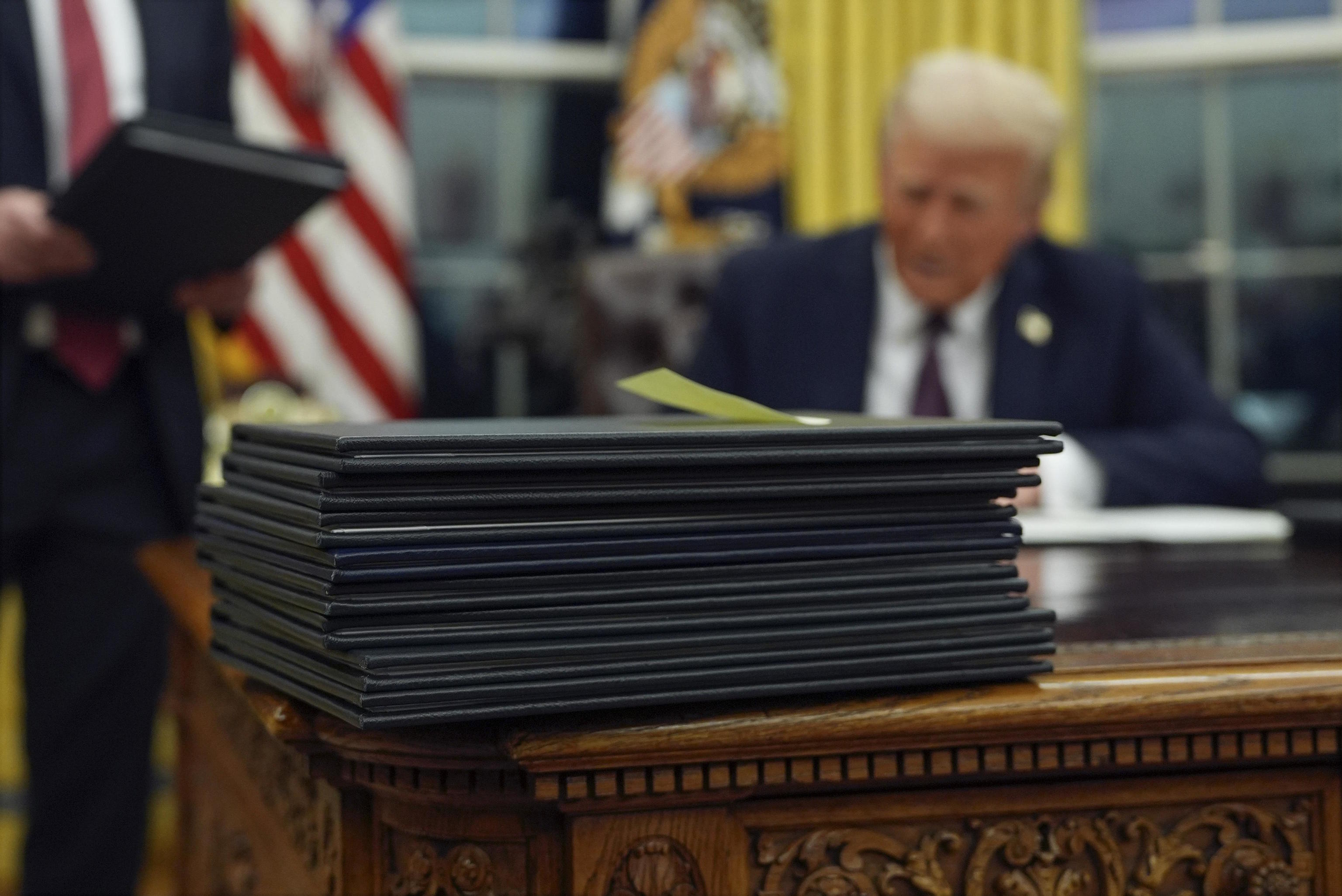 President Trump signs executive orders in the Oval Office of the White House.