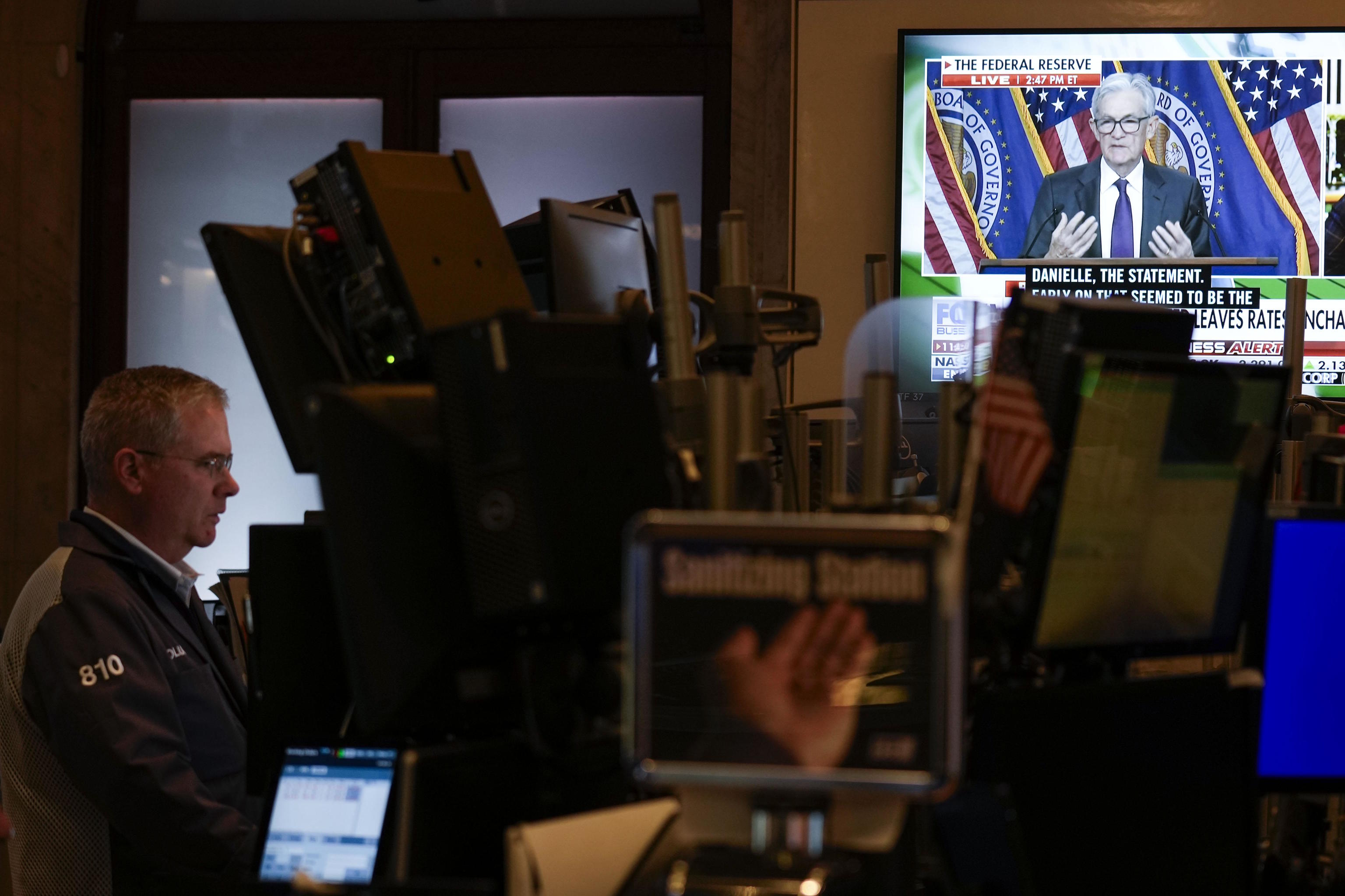 Screens display a news conference by Federal Reserve Chair Jerome Powell.