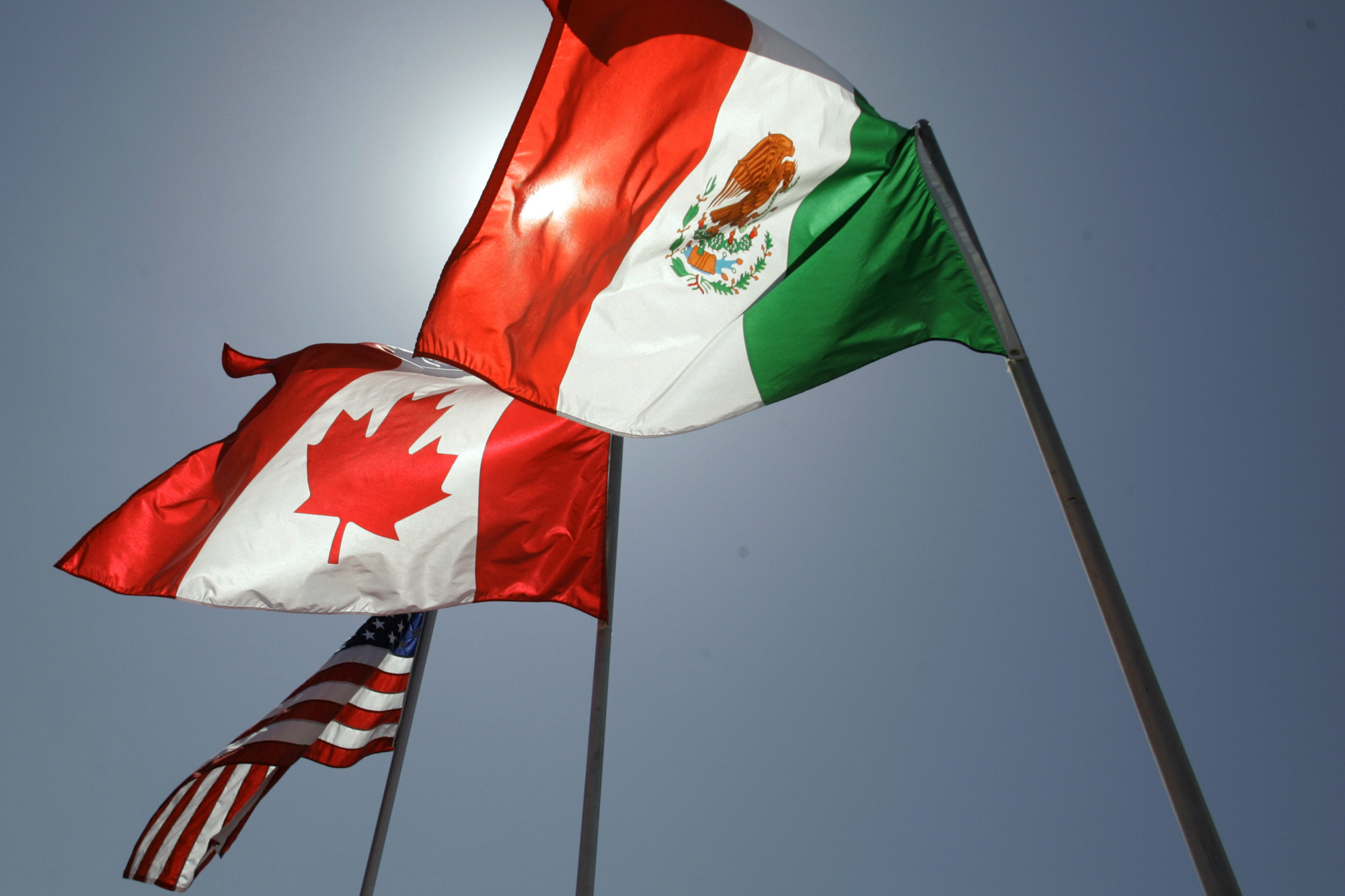 National flags representing the United States, Canada, and Mexico fly in the breeze.