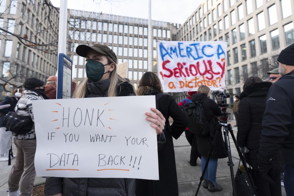 Protesters hold banners during a rally in front of the Office of Personnel Management