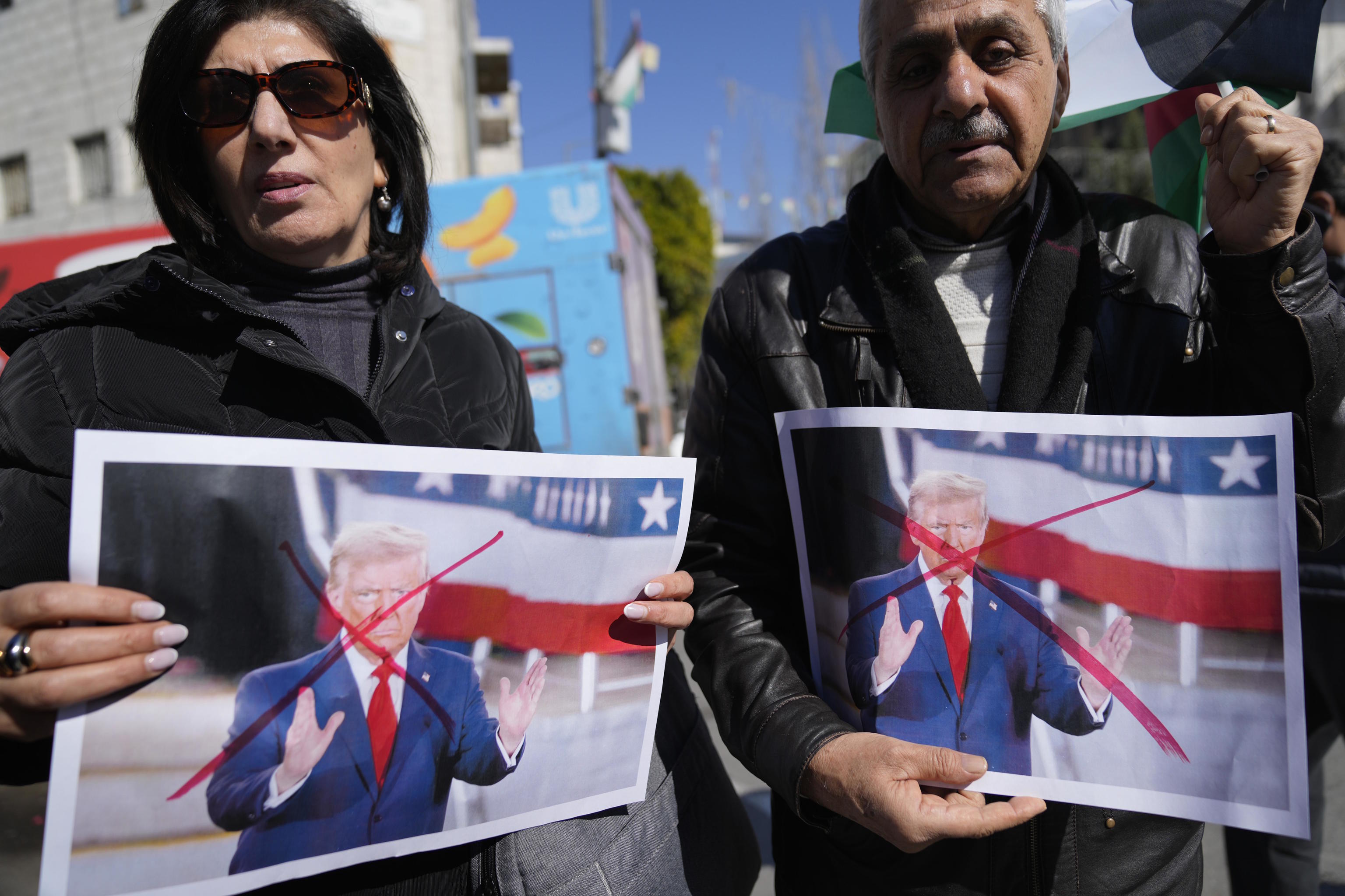 Palestinians carry defaced pictures of U.S. President Donald Trump.