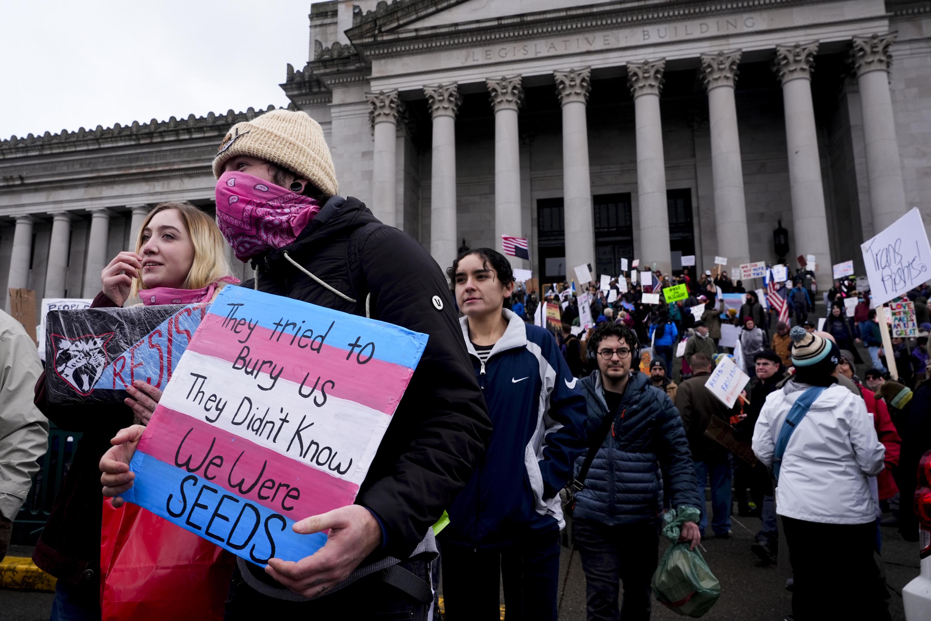 A protester holds a sign with the colors of the transgender flag.