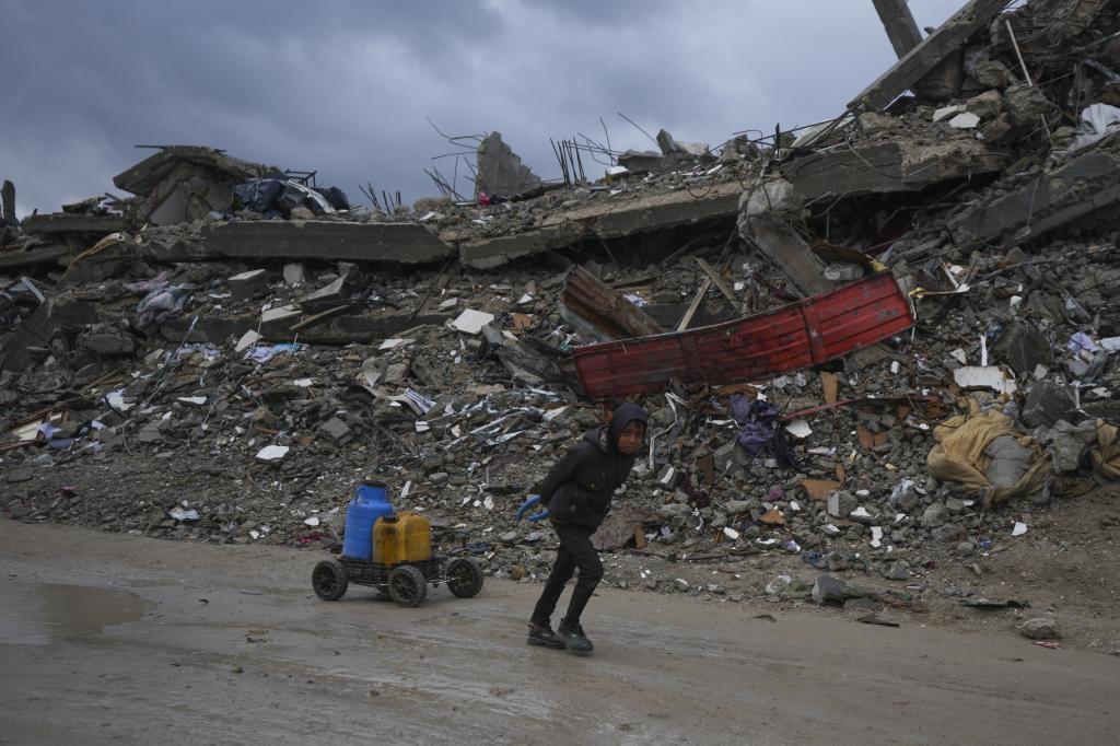 A young Palestinian kid carries water along the destruction caused by the Israeli air and ground offensive in Jabaliya, Gaza