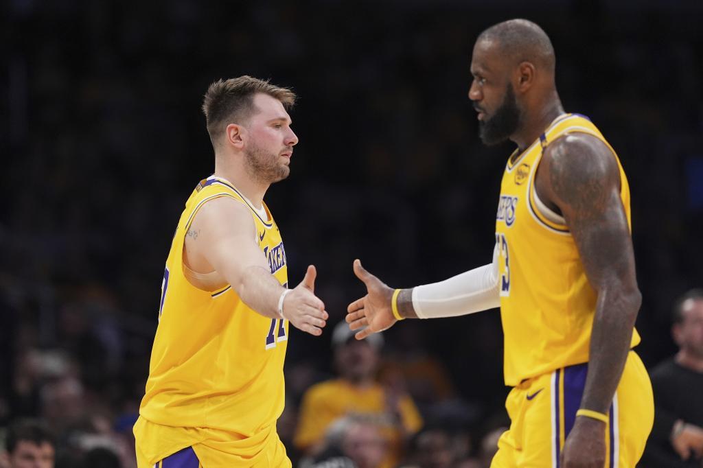 Los Angeles Lakers guard Luka Doncic, left, touches hands with teammate forward LeBron James