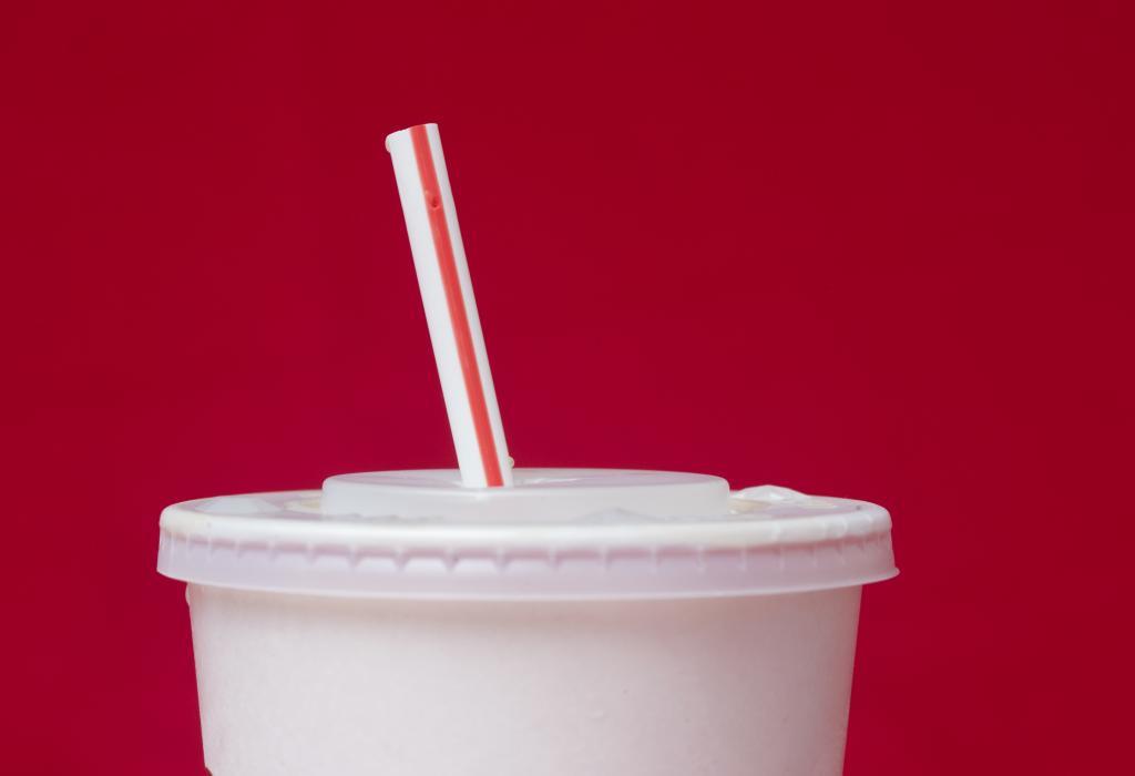 A large soft drink with a plastic straw.