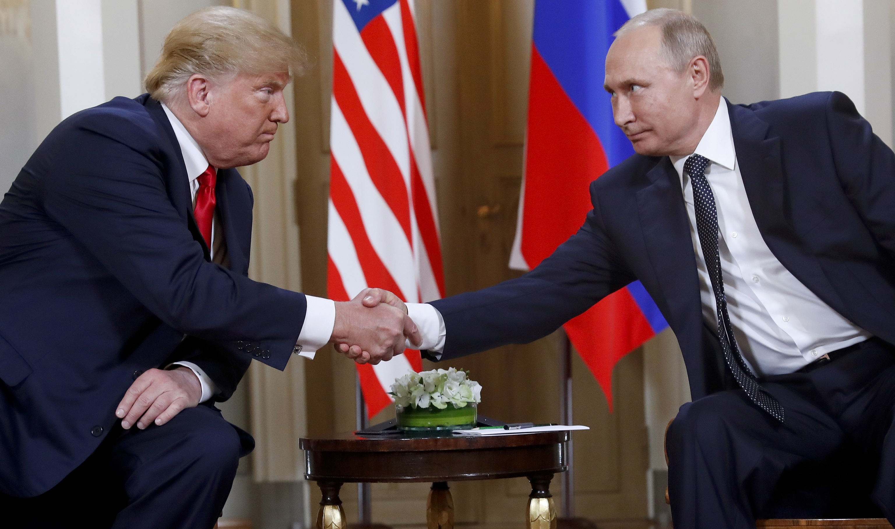 resident Donald Trump, left, and Russian President Vladimir Putin shake hands.