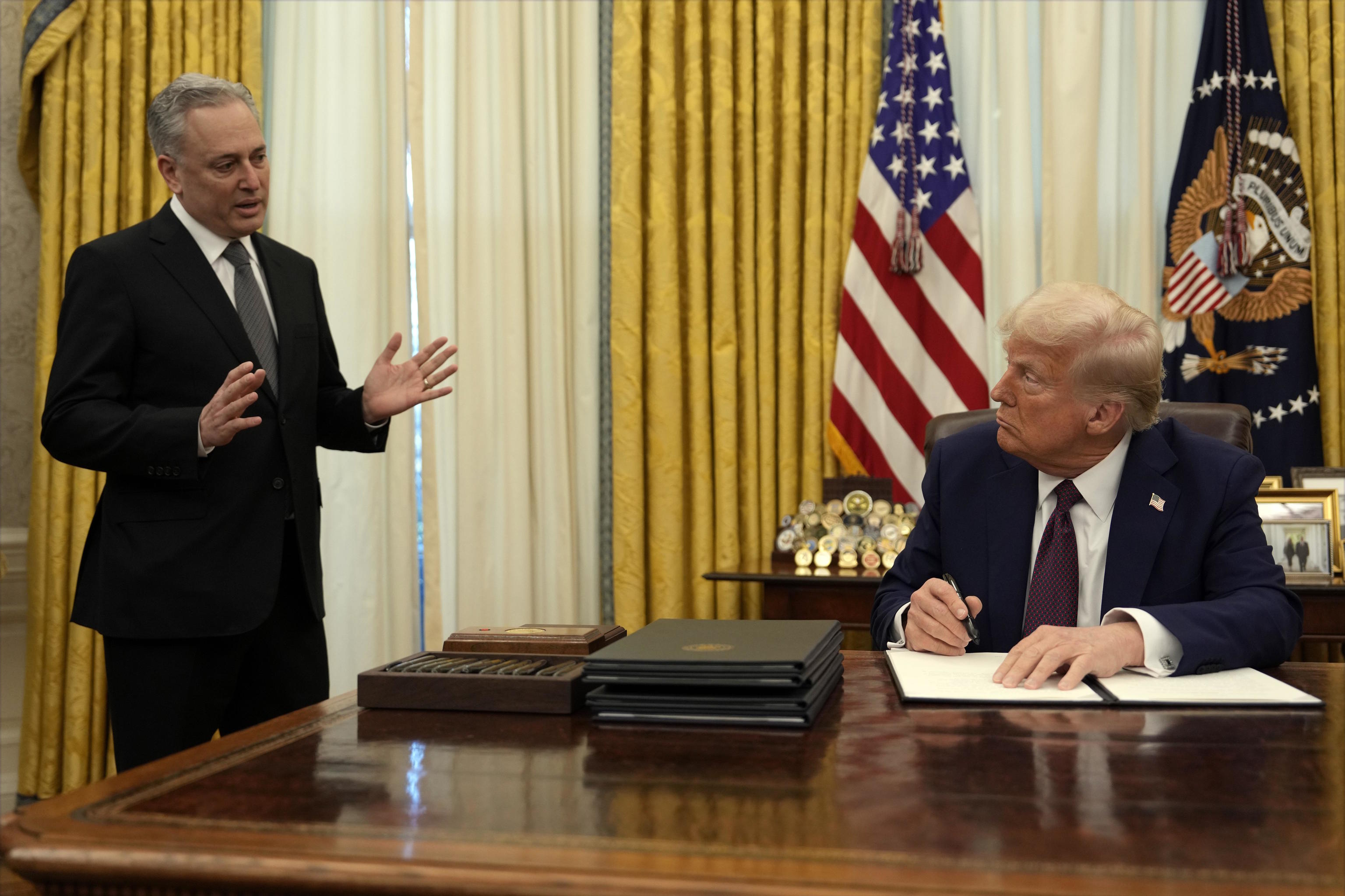 Trump listens to White House adviser David Sacks as he signs an executive order.