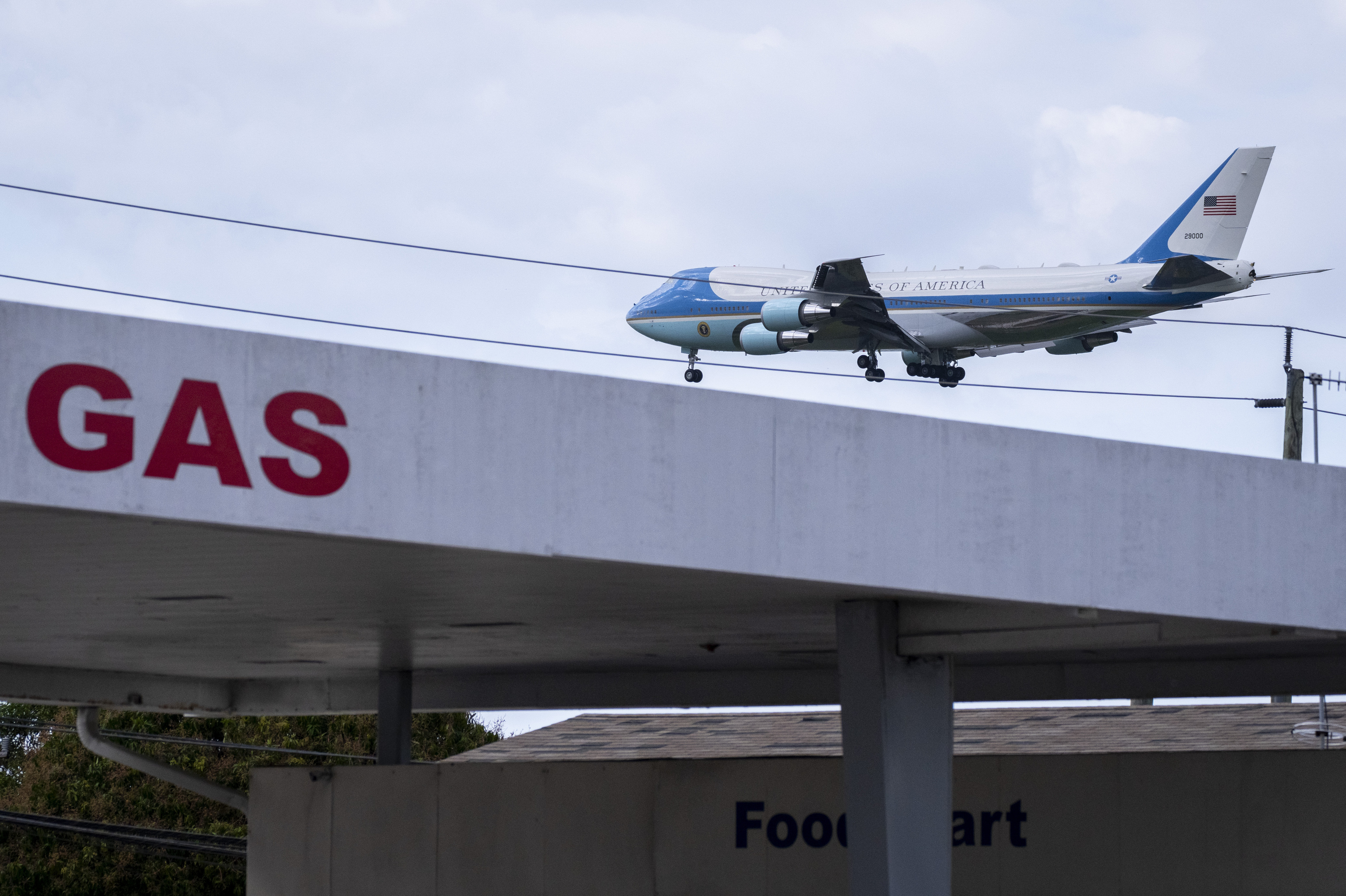 Air Force One with President Donald Trump on board is seen above a gas station.