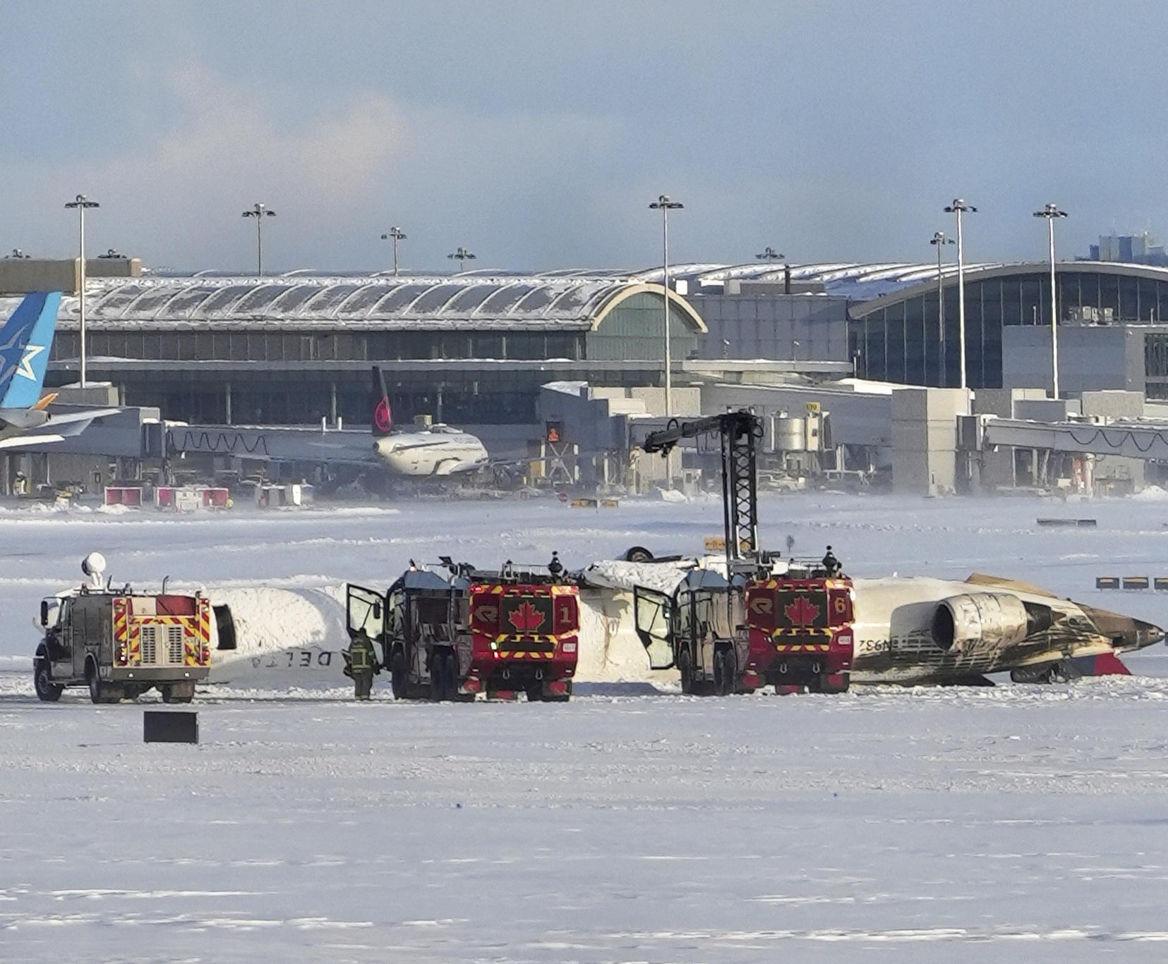 An aircraft from Delta Airlines sits upside down on the tarmac at Toronto Pearson International airport.