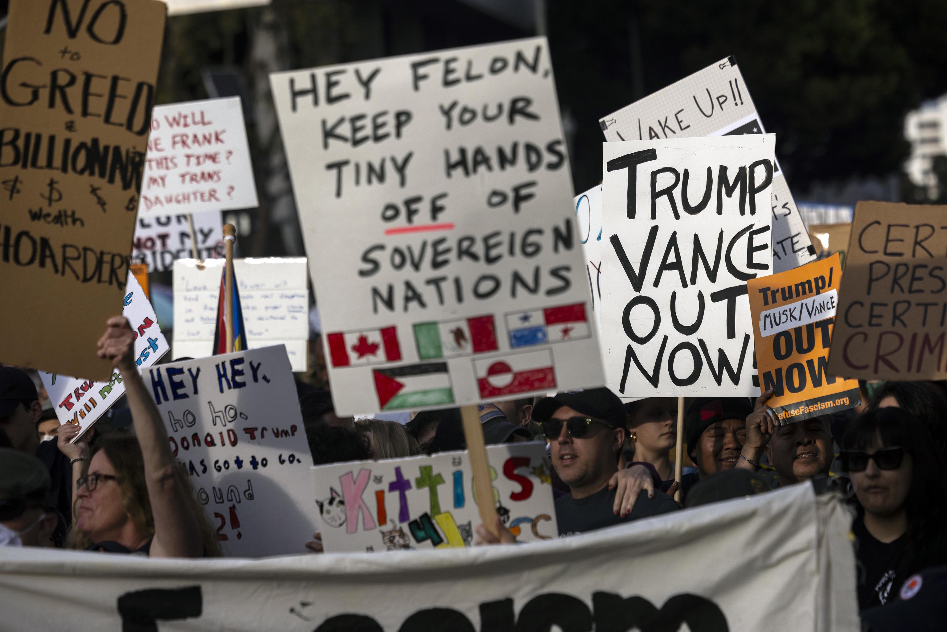 Demonstrators march holding posters during a rally to protest President Trump 'spolitics on Presidents Day'.