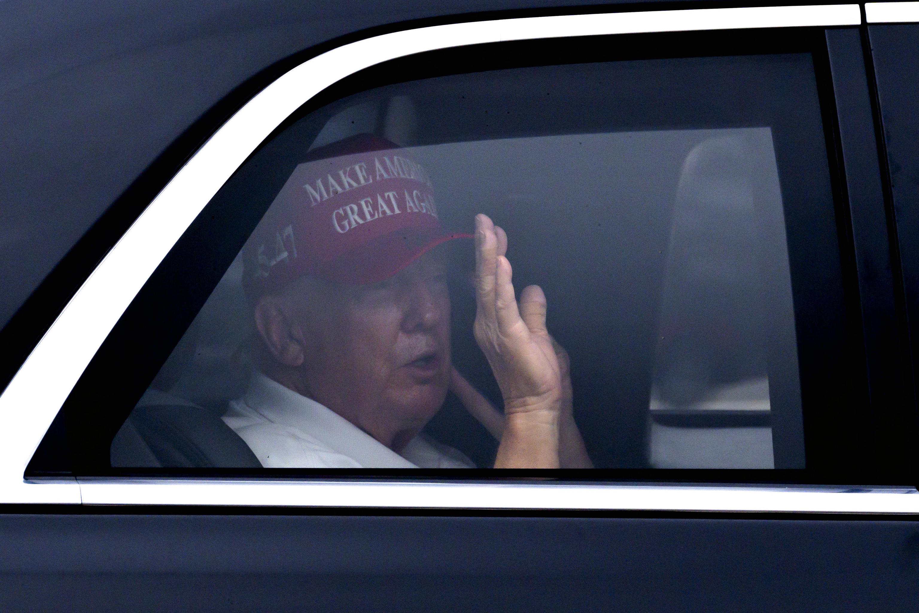 President Donald Trump waves from his vehicle.