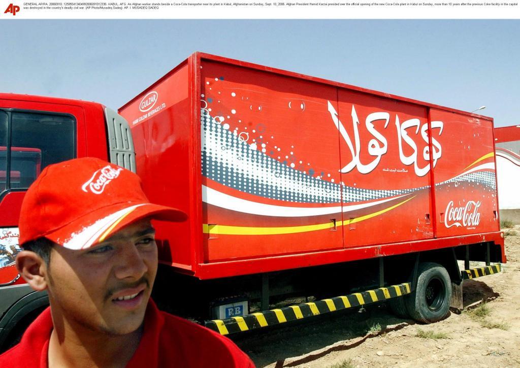 An Afghan worker stands beside a Coca-Cola transporter near its plant in Kabul,