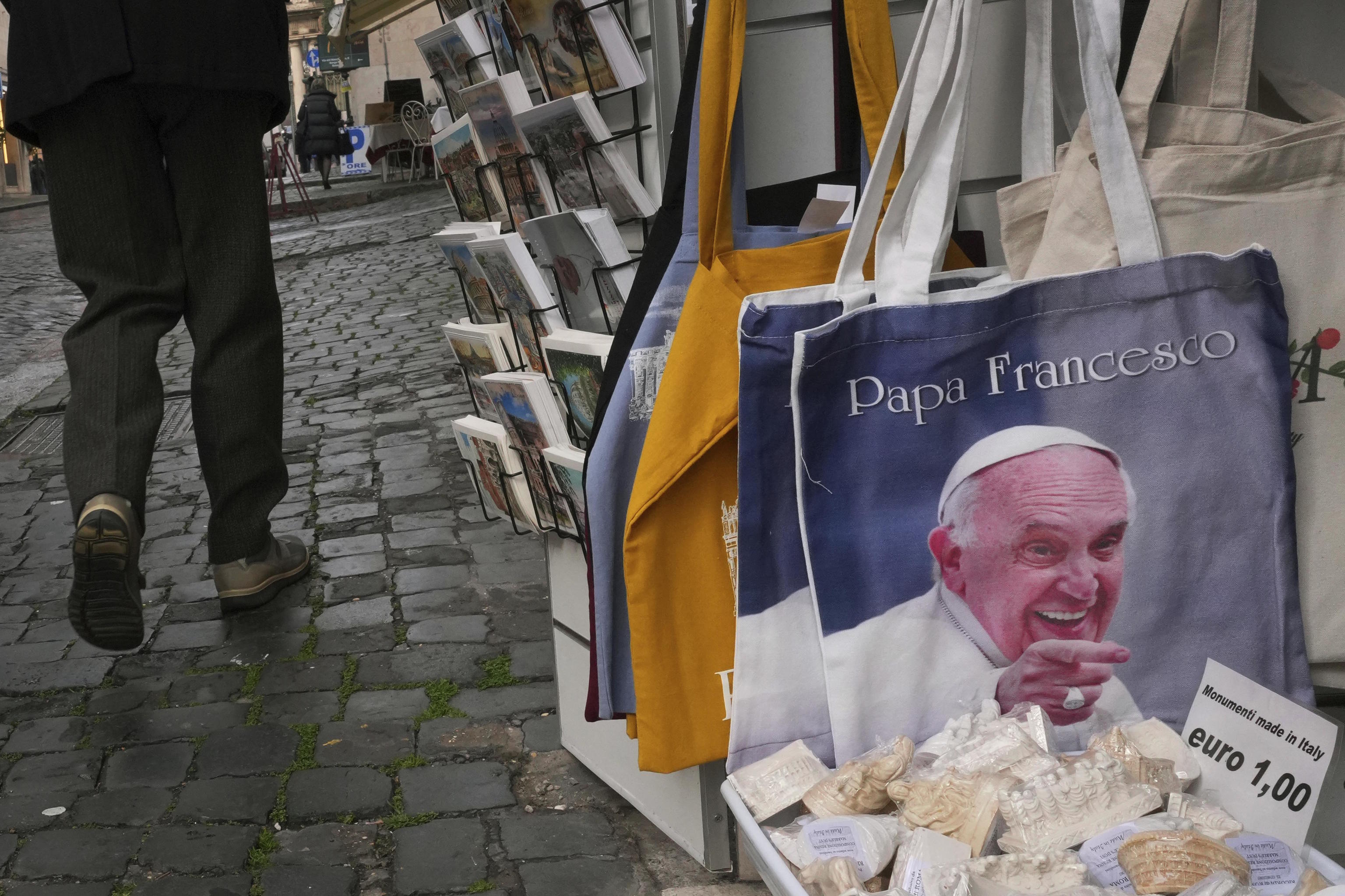 Pedestrians pass a shop selling Pope Francis souvenirs in Rome.