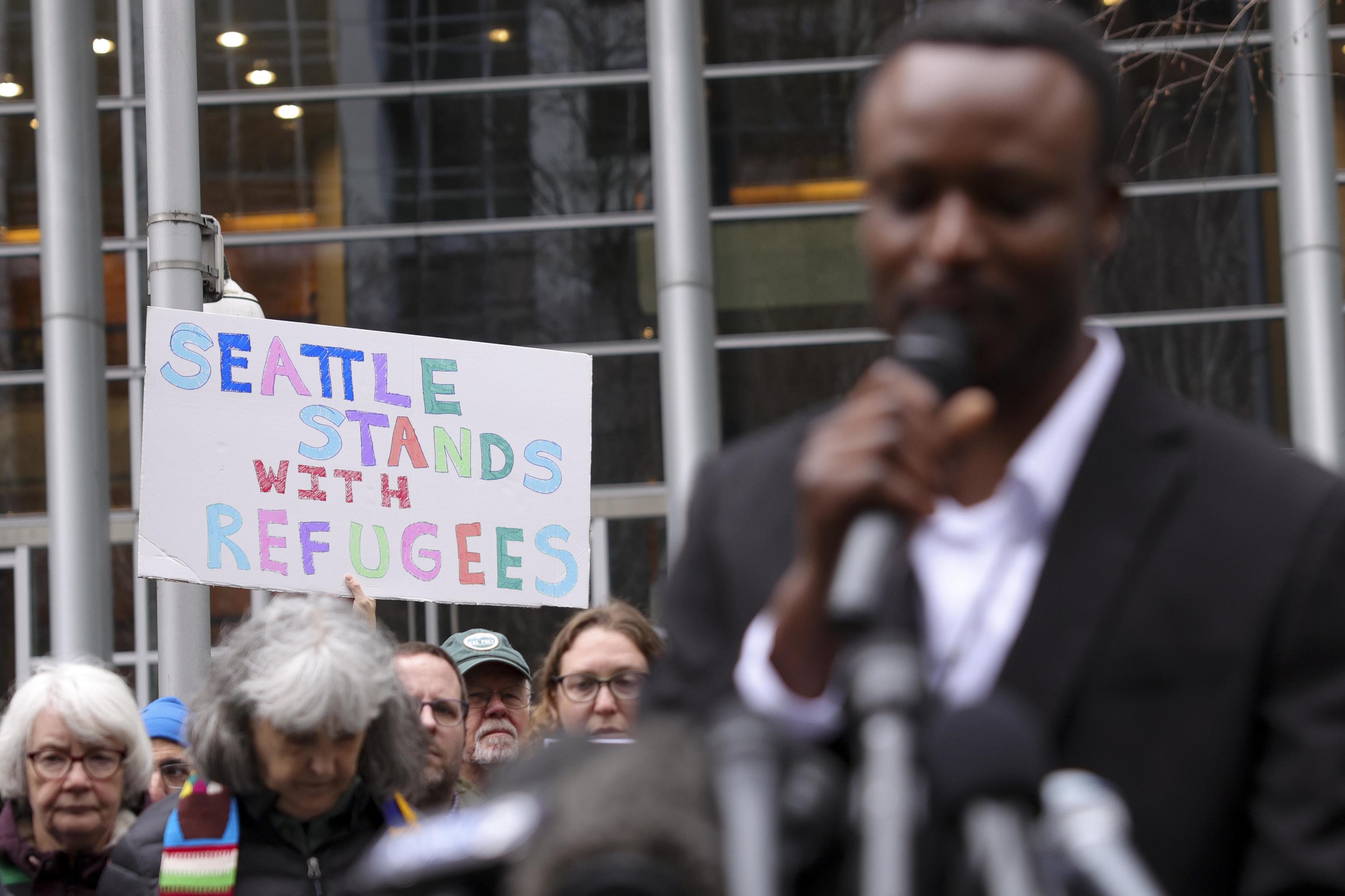 A person displays a sign supporting refugees at a rally.