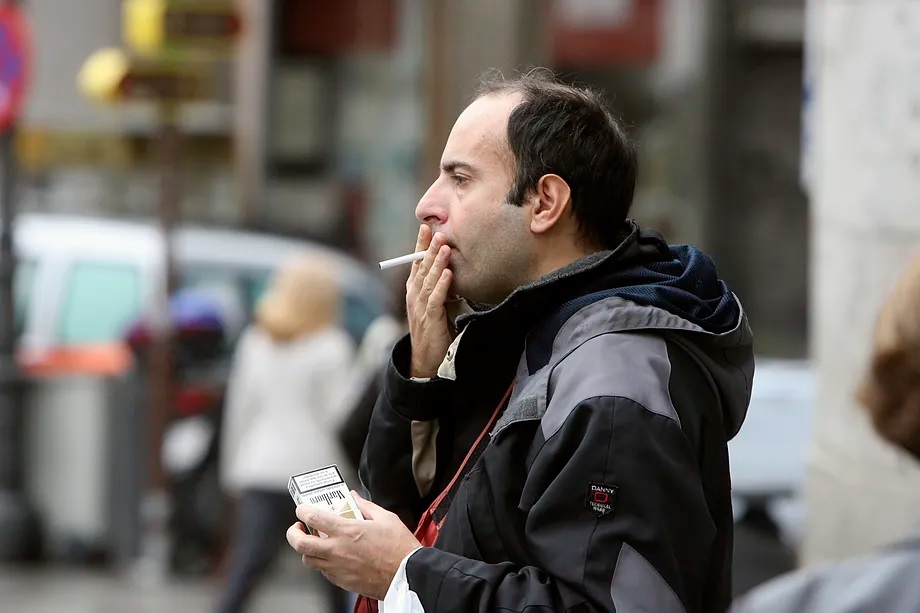 A man lights a cigarette in the middle of the street