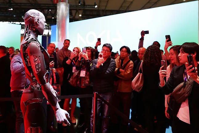 A group of attendees photograph a robot at last year's edition of the Mobile World Congress.