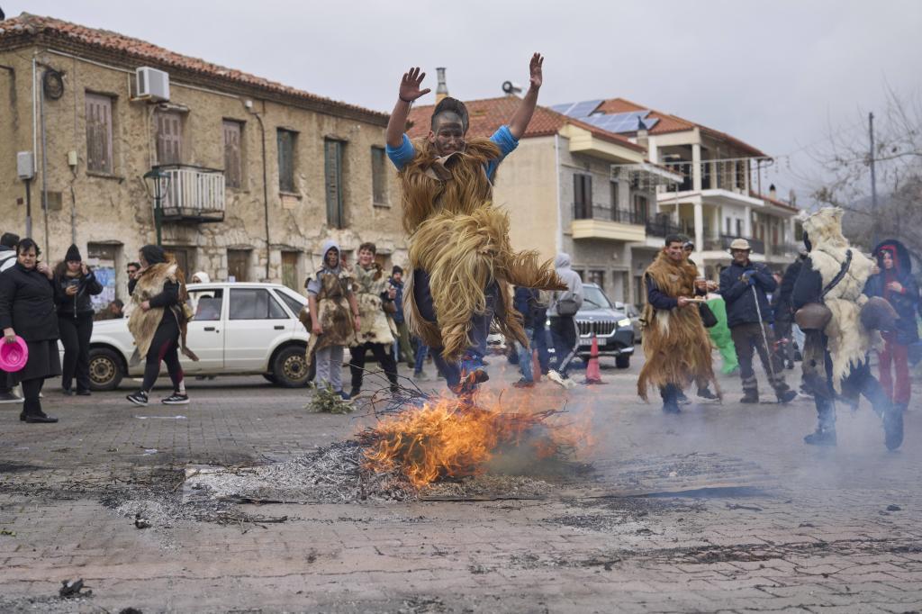 A man dressed in animal skins and heavy bronze bells, jumps over a burning carnival effigy during carnival celebrations in Distomo, a village in central Greece