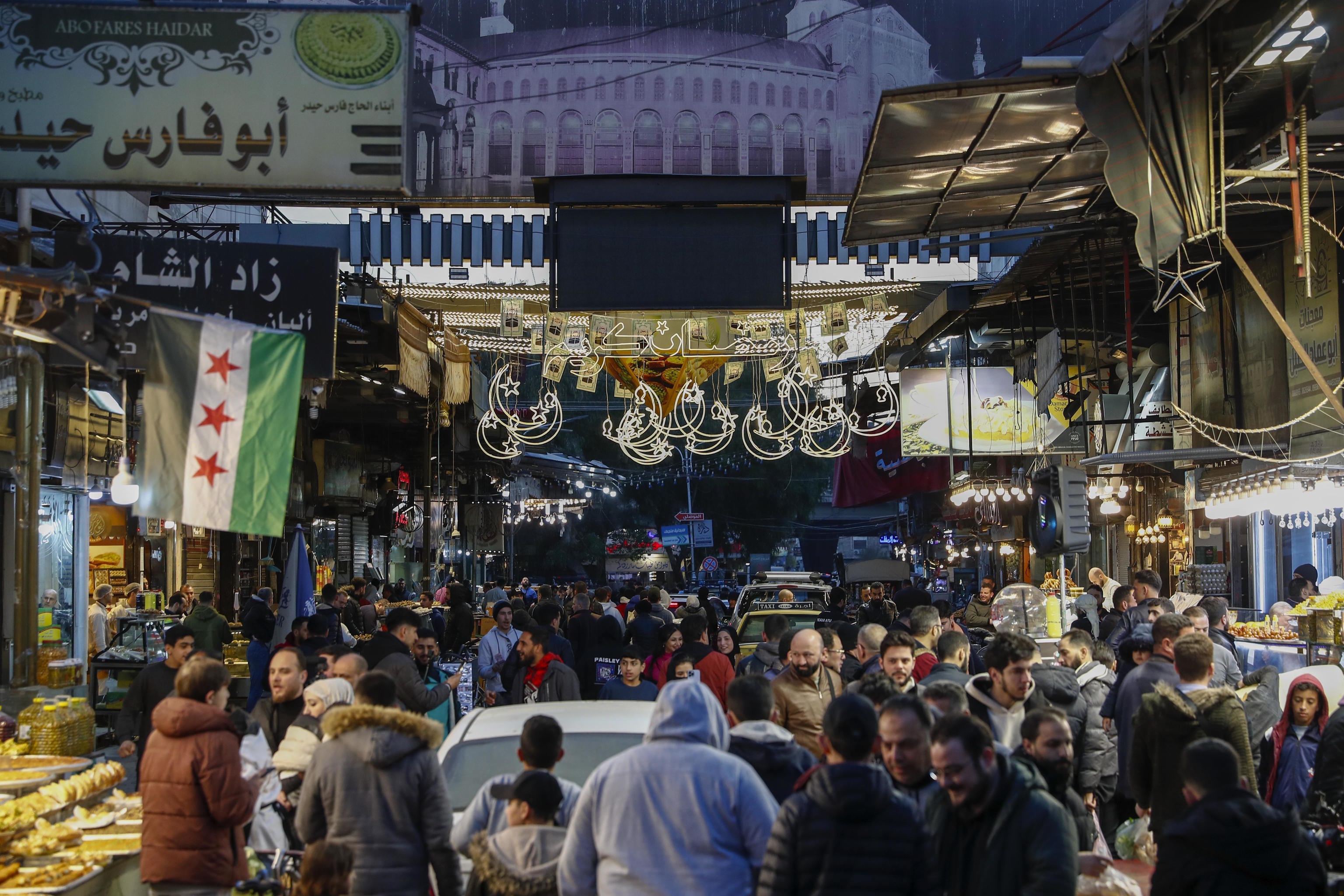 Residents walk in the market on the first day of Ramadan, in Damascus.