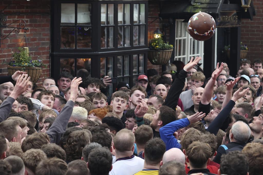 The ball is thrown high above the crowd of players who try to reach it during the annual Shrovetide medieval soccer match in Ashbourne