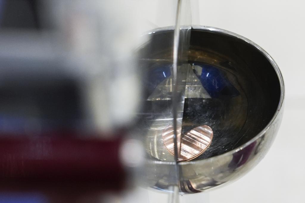 A souvenir penny falls out of a penny press machine