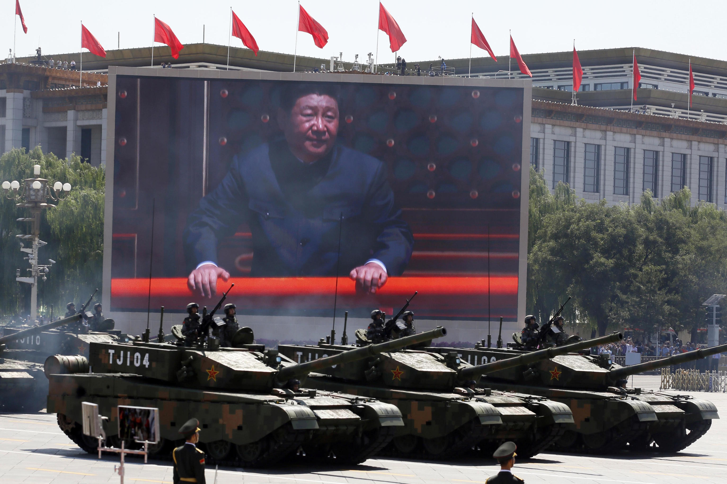 Xi Jinping is displayed on a screen as battle tanks take part in a parade.