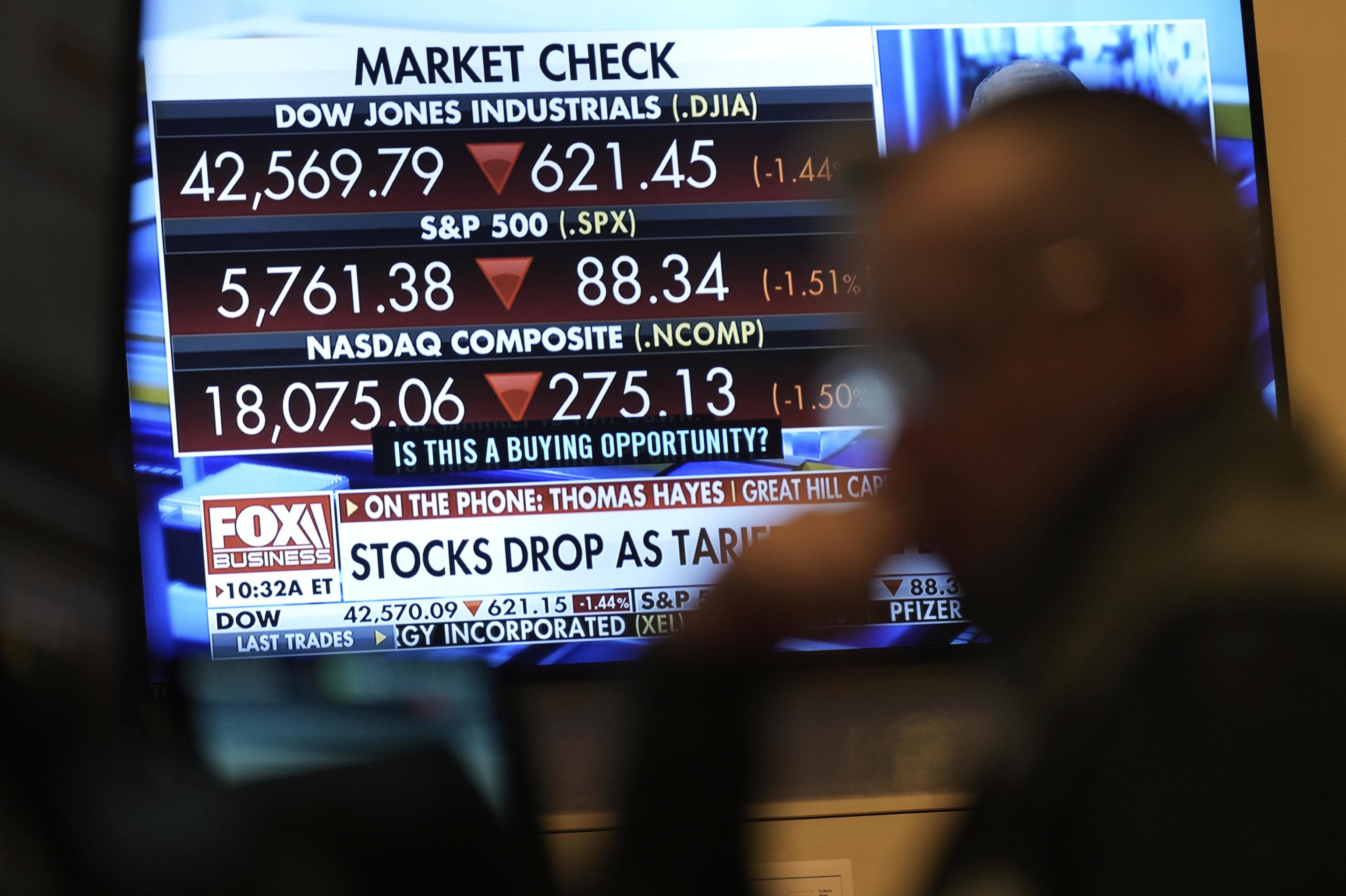 Financial news is displayed as people work on the floor at the New York Stock Exchange.