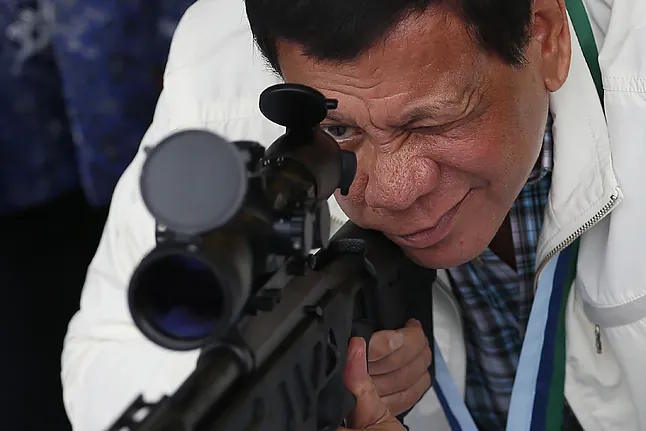 Filipino President Rodrigo Duterte checks the scope of a sniper rifle.