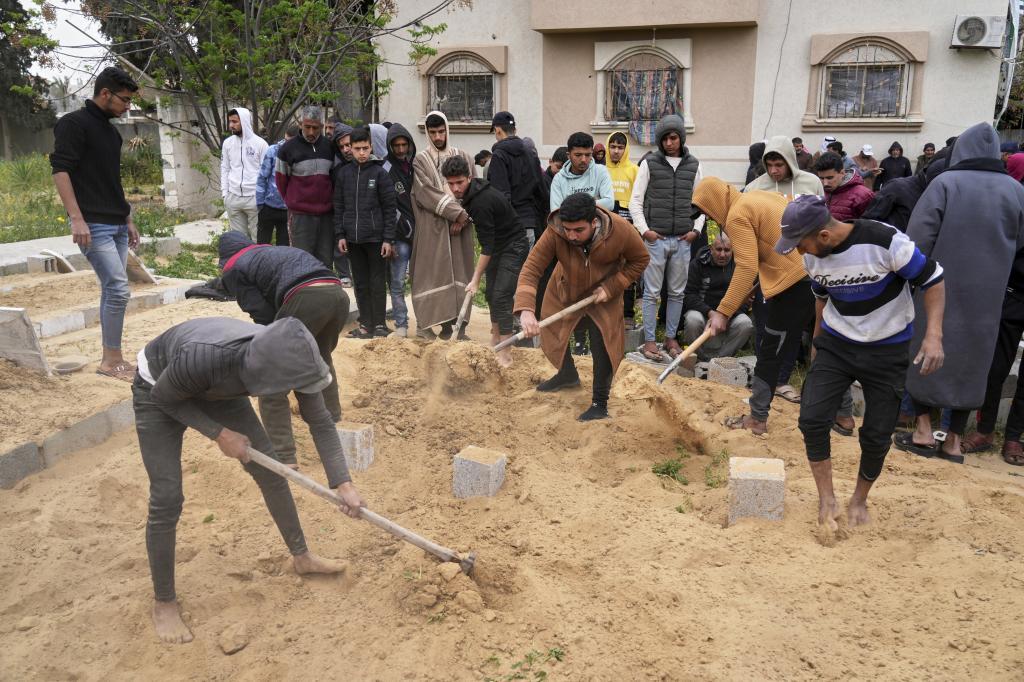 Palestinians cover the grave of a group of victims of Israeli army strikes