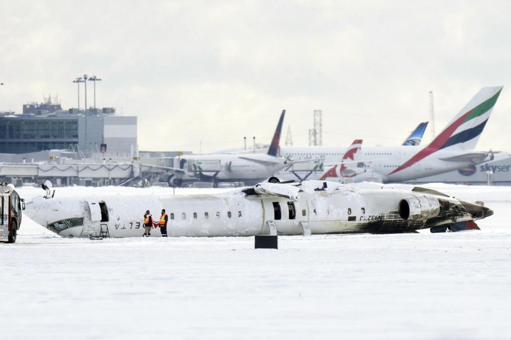 A Delta Air Lines plane lies upside down at Toronto Pearson Airport