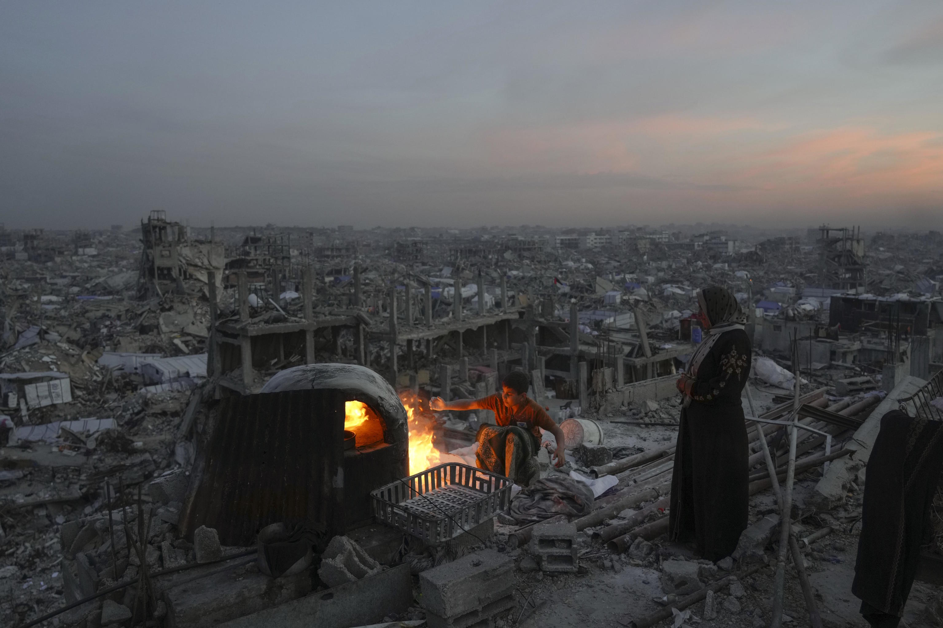 Ali and his mother cook on a fire on the roof of their house.