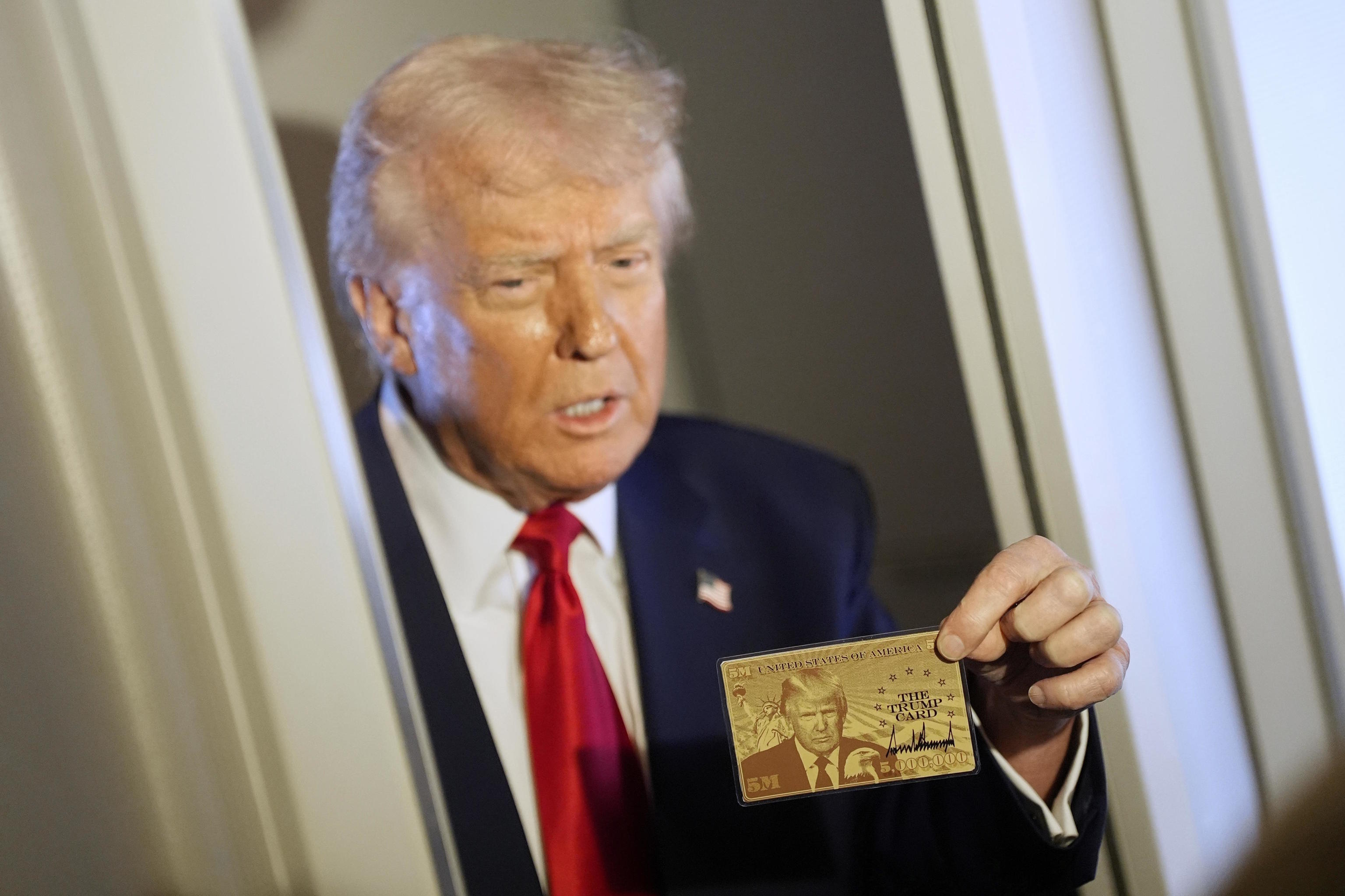 President Donald Trump holds up the $5 million gold card.