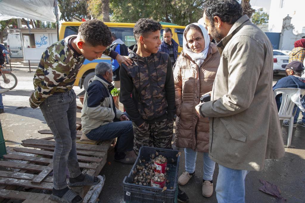 Customers buy snails at a weekly market in Enfidha