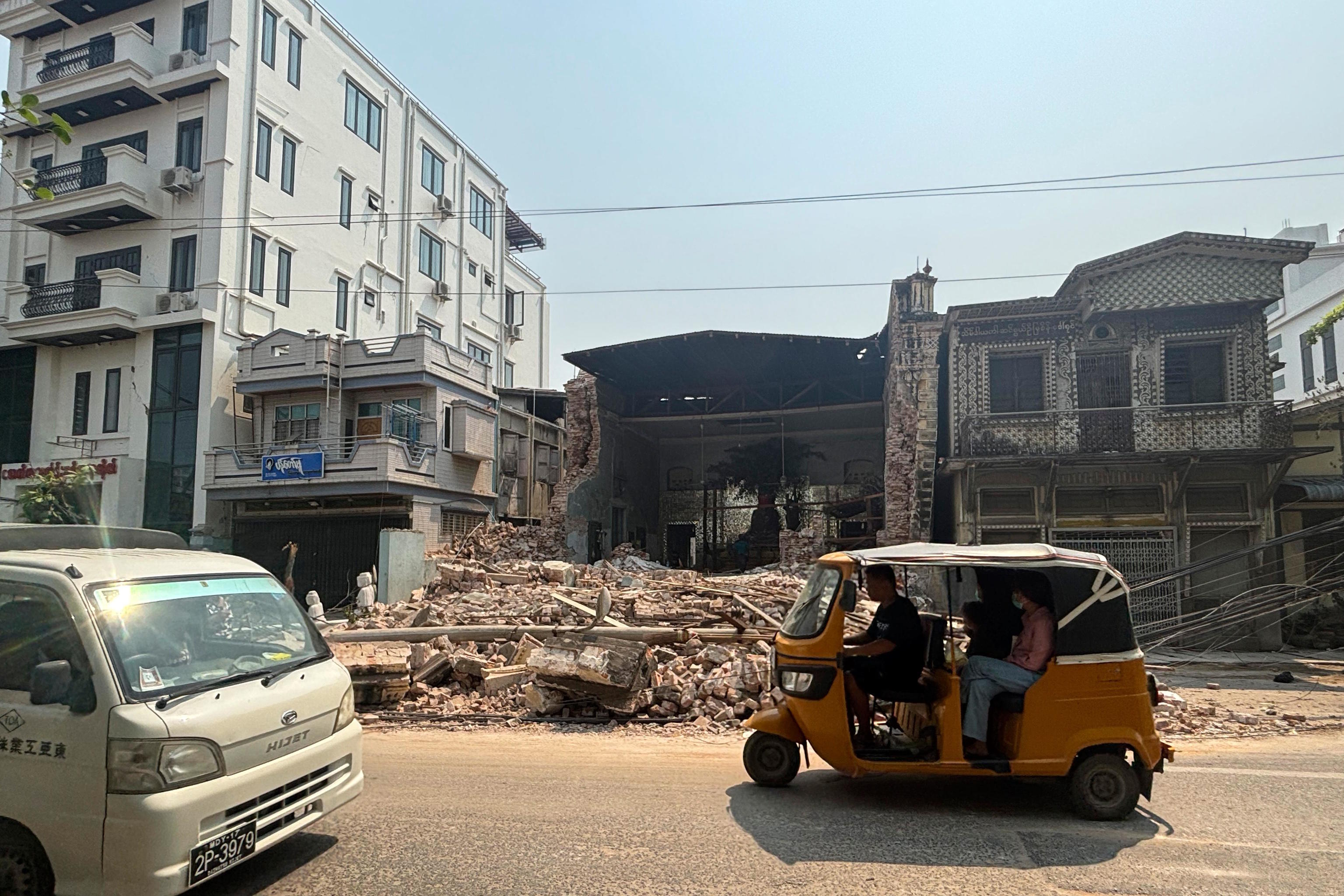 Local residents ride past a damaged building in Mandalay.