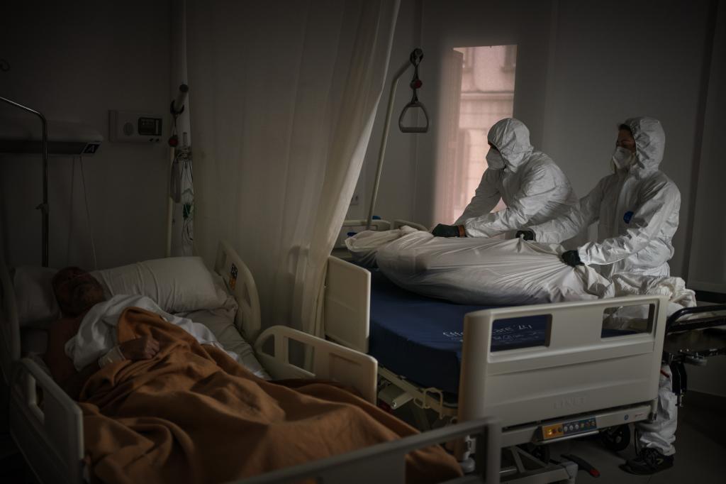 Wearing protective suits, funeral home workers remove the body of an elderly person who died of COVID-19