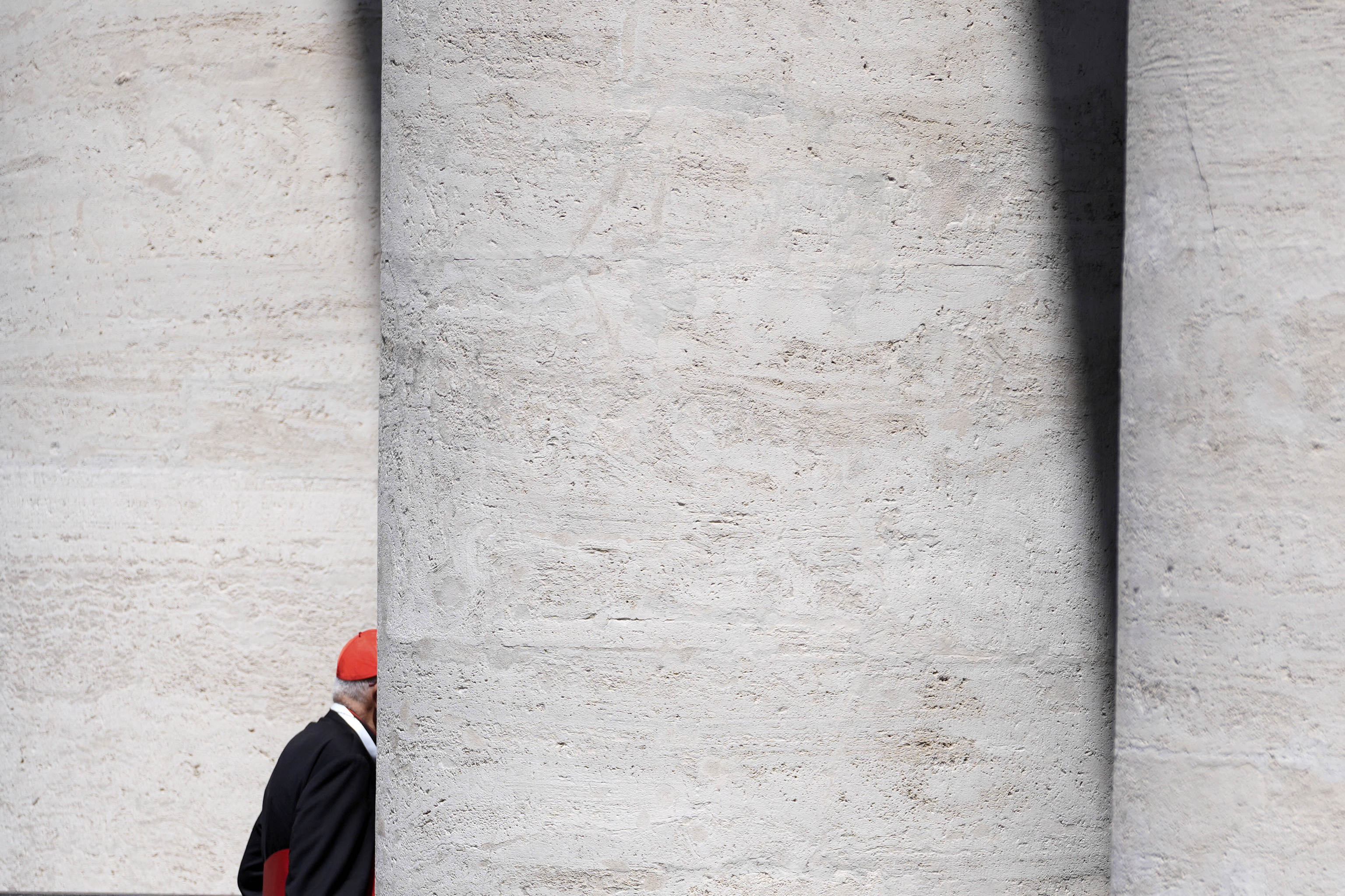 An unidentified Cardinal walks through the St. Peter's Square colonnade at the end of a college of cardinals' meeting.