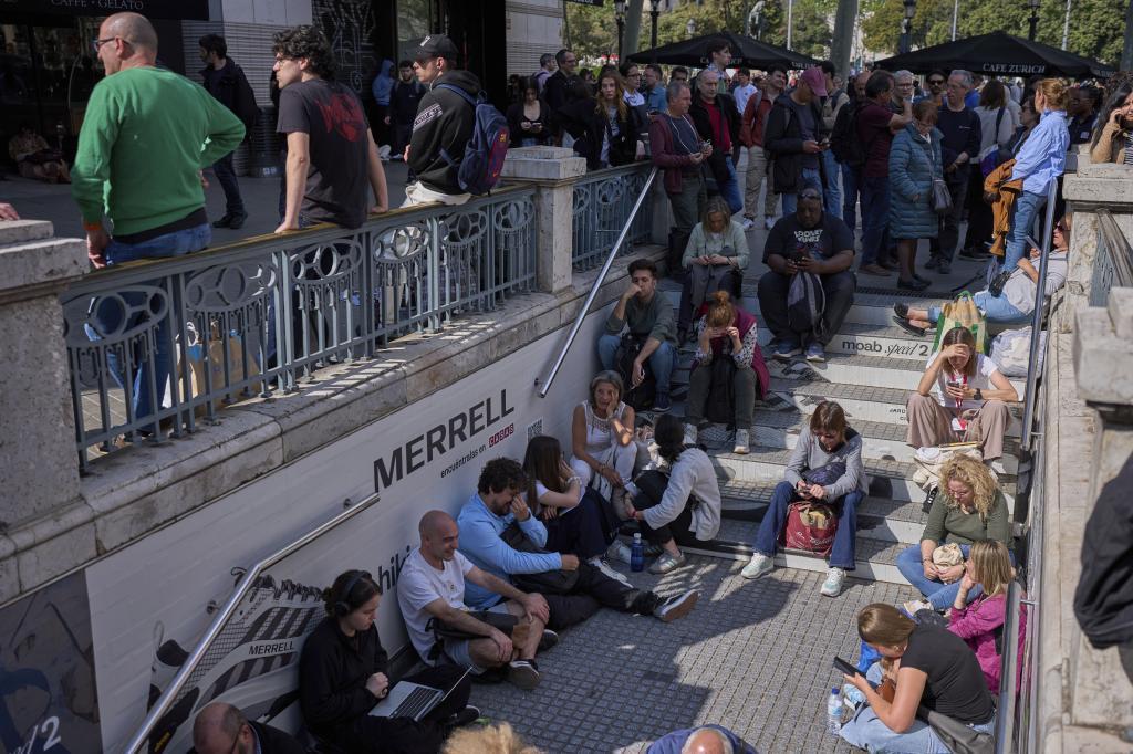 People wait outside a closed metro station, during a blackout in Barcelona