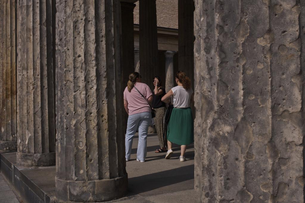 Tourists stand between the columns on Museum Island with holes from artillery fire from World War II, in Berlin