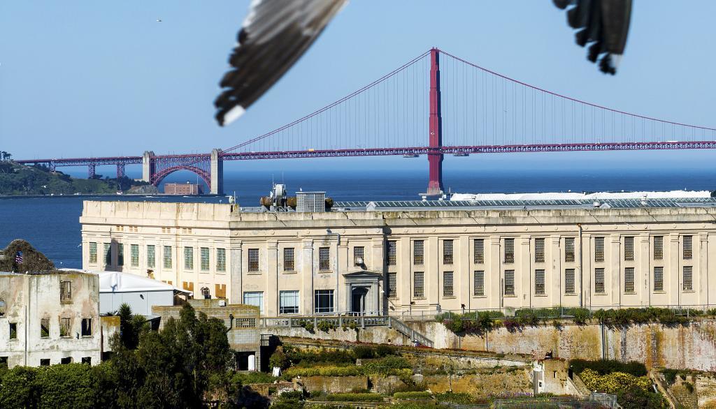 The Golden Gate Bridge stands behind the cell house at Alcatraz Island