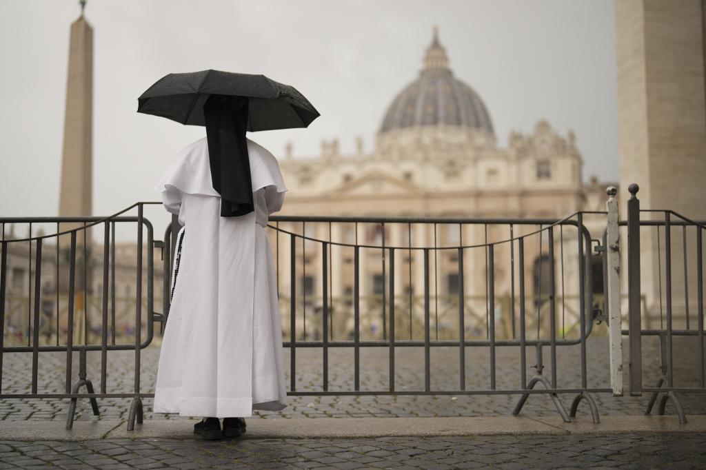 A nun shelters from the rain as she follows a final Mass celebrated by cardinals inside St. Peter's Basilica