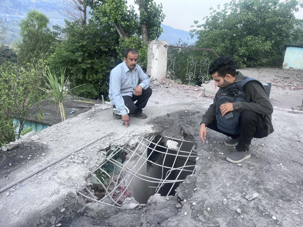 Indian villagers living near the Line of Control between India and Pakistan look at a hole on the roof of a house caused by a Pakistani shell