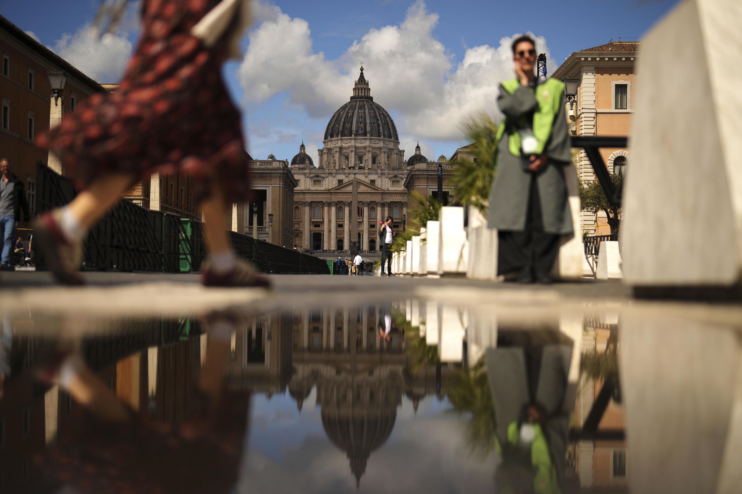 Several people walk around St. Peter's Basilica in the Vatican.