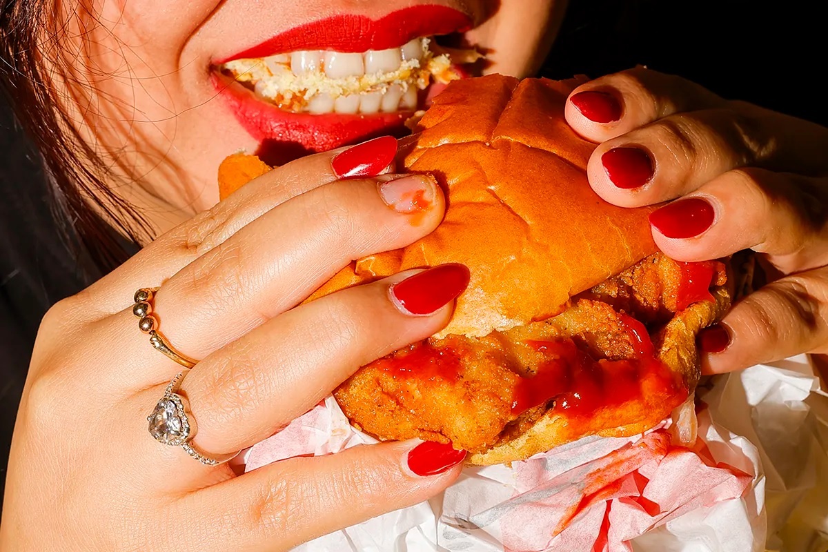 A woman eats a hamburger.