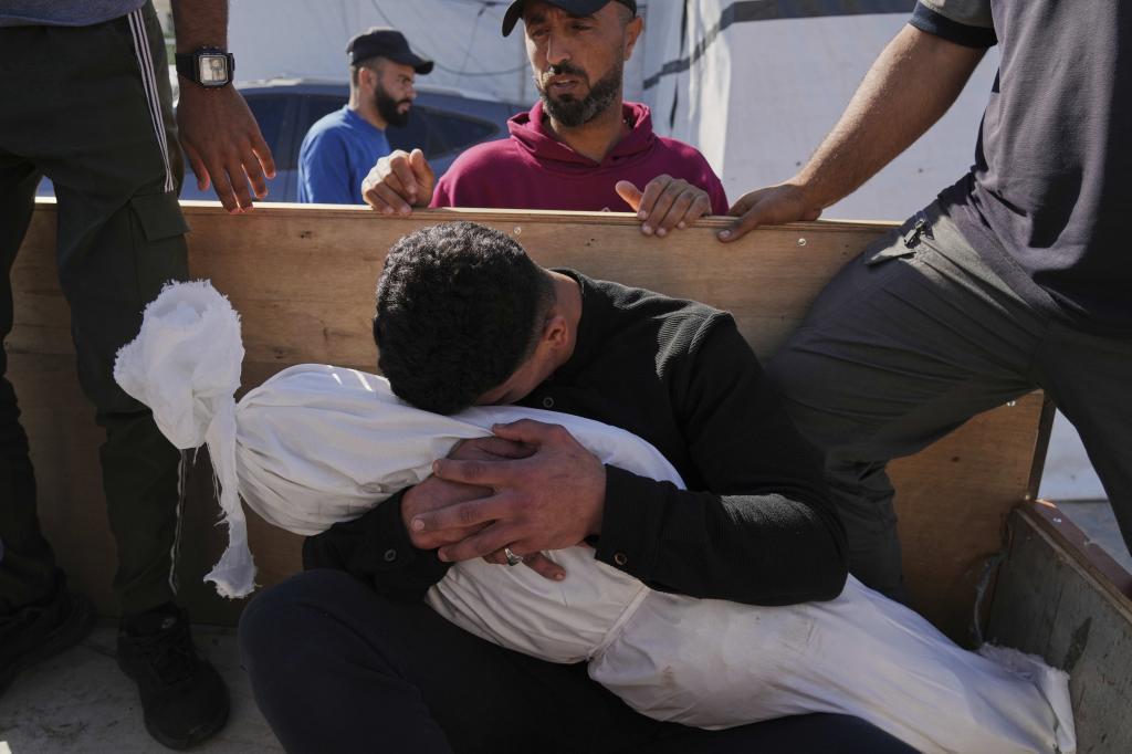 A Palestinian man embraces the body of his 5-year-old son, Adam Namrouti, who was killed in an overnight Israeli airstrike on a UN school