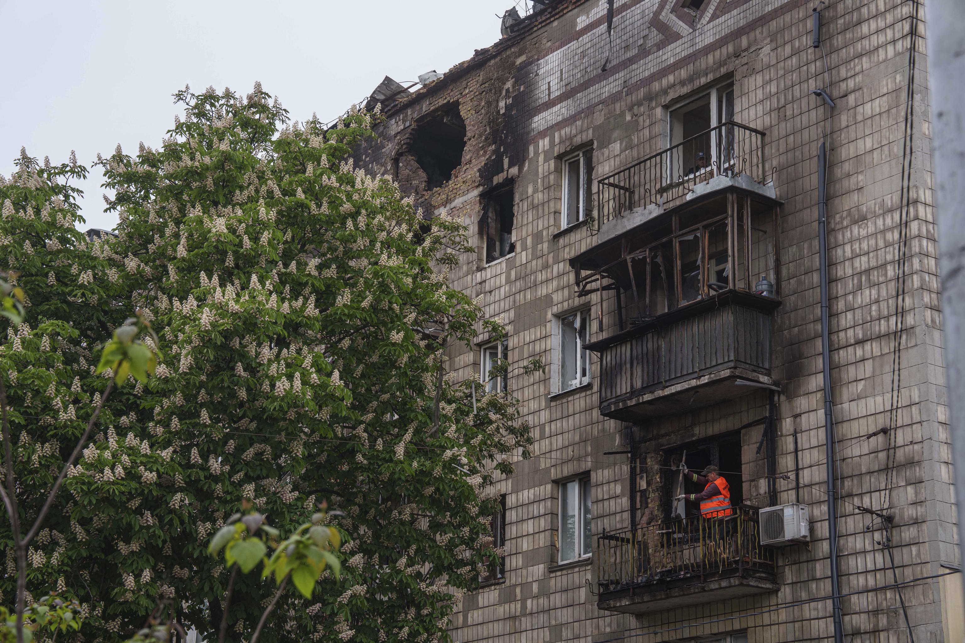 A municipal worker clears the rubble from a balcony of a residential building, damaged after a Russian strike, in Kyiv.
