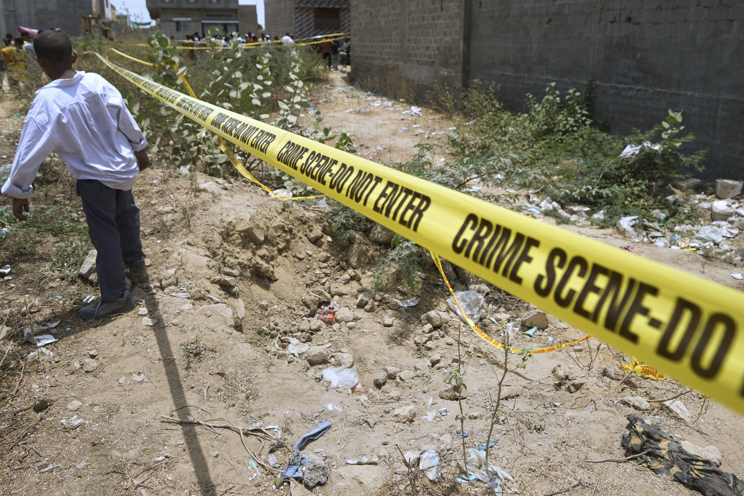 Local residents gather near a cordon off site, where Pakistan's air defense system shot down a suspected Indian drone.