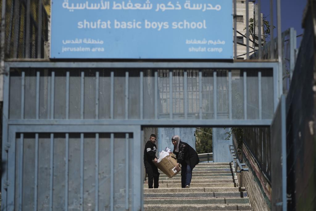 A student and a teacher carry study material at UNRWA Girls School run by the U.N. agency for Palestinian refugees